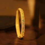 Bracelet-style bangle with golden green gemstones and ethnic floral pattern